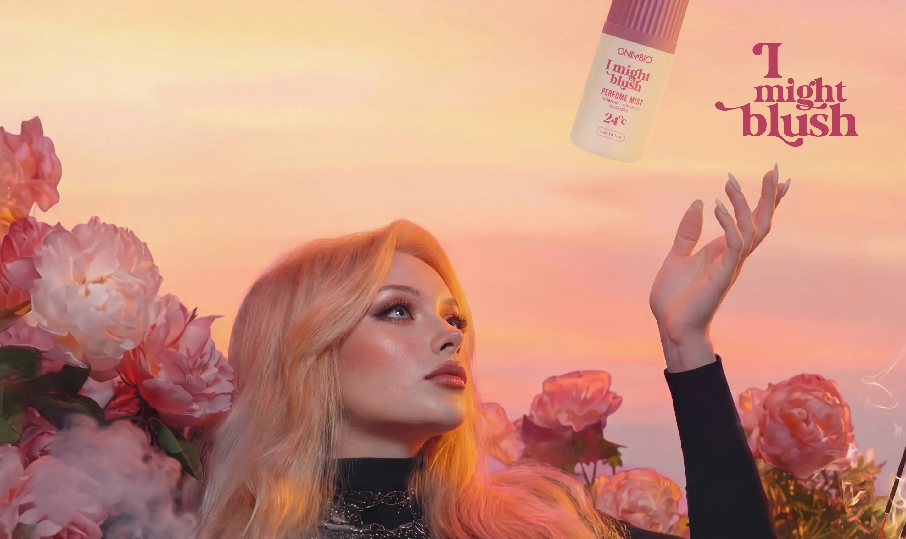 Modelka leży pośród piwonii na tle pastelowego nieba, patrząc na unoszącą się mgiełkę perfumowaną ONLYBIO I Might Blush.